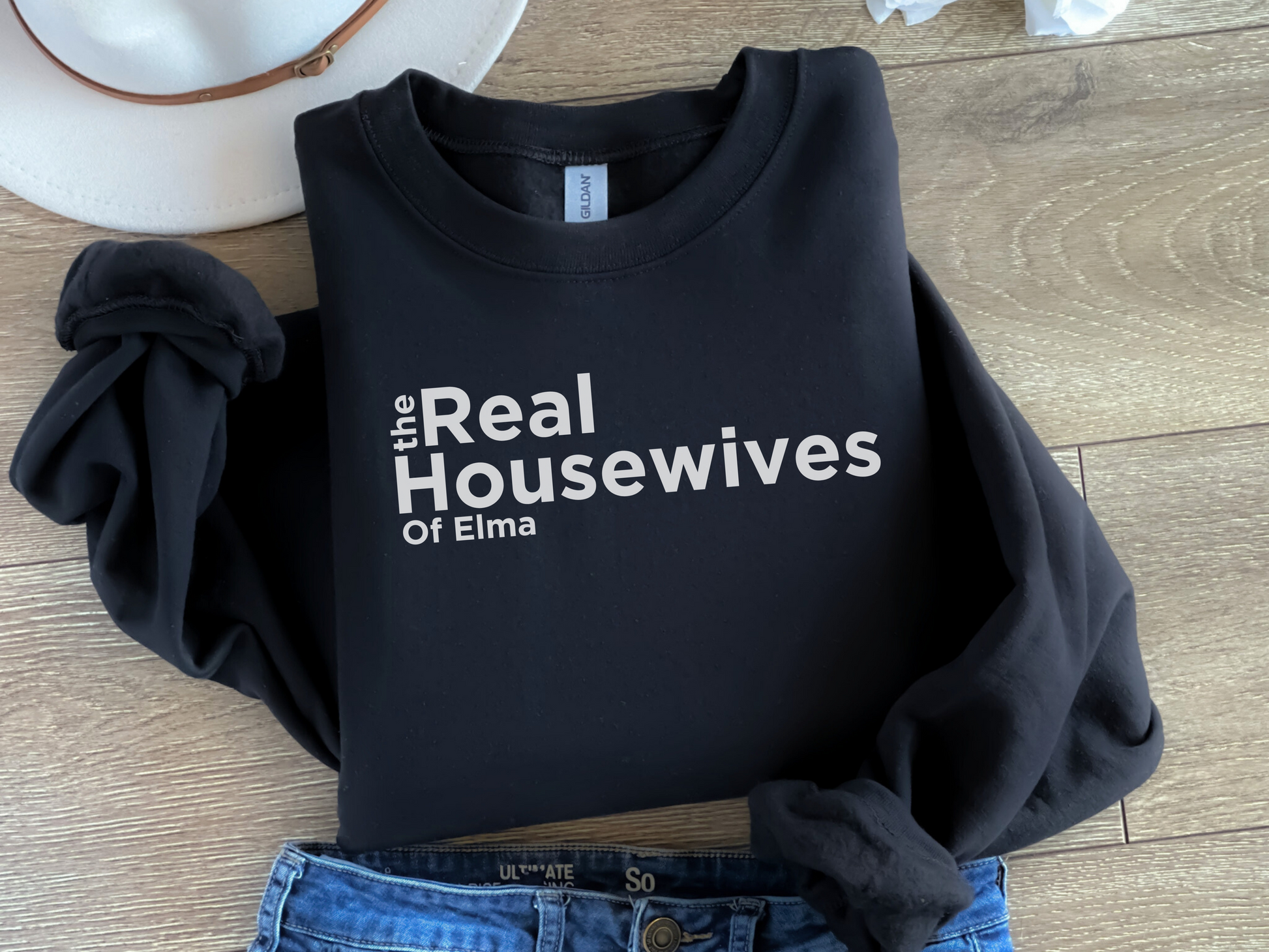 Women’s black crewneck sweatshirt with white text across the chest that reads “the real housewives of Elma.”